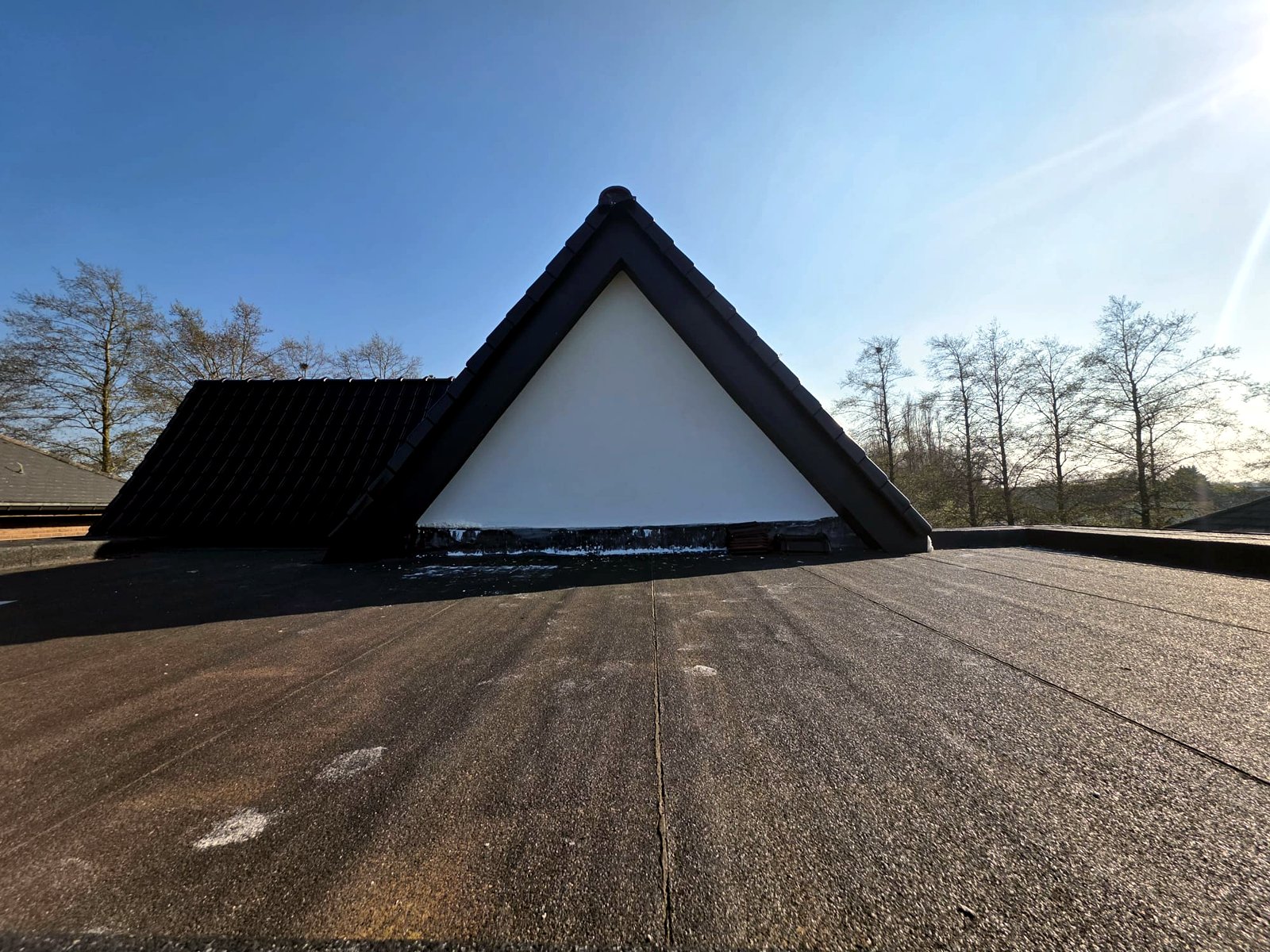 Toiture neuve en tuiles noires posée par Belara Construct, avec étanchéité de toit plat, en Flandre